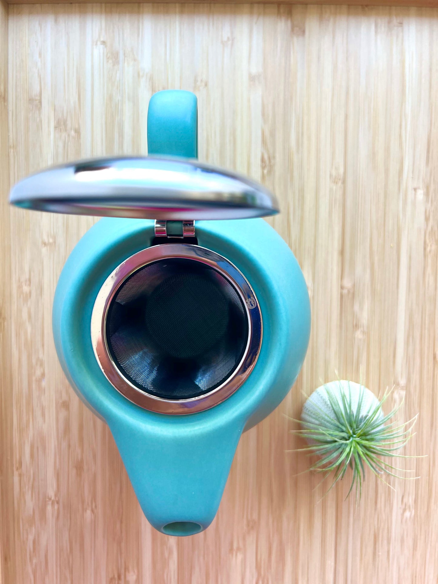 light blue teapot open to reveal stainless steel strainer